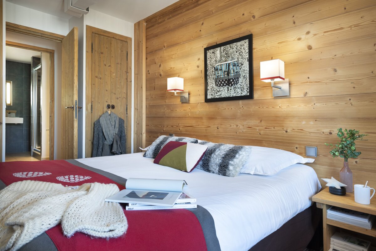 A bed with a red blanket and a book on it