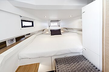 A white bed with a black pillow on it