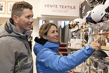 A man and a woman are looking at skiwear in a store