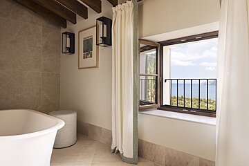A bathroom with a bathtub and a window looking out to the ocean