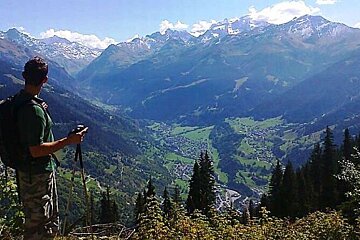 A man with a backpack stands on top of a mountain overlooking a valley