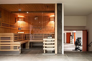 A wooden sauna with a glass door in a gym
