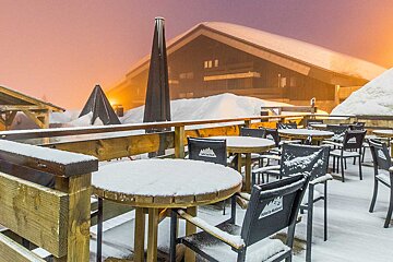 Snow covered tables and chairs in front of a snow covered building