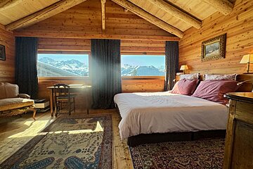 A bedroom with a large bed and a view of the mountains