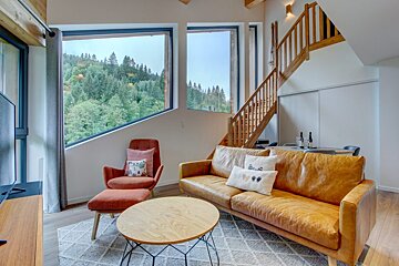 A living room with a brown leather couch and a red chair