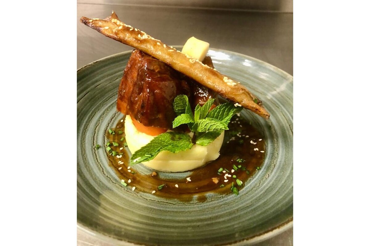 A plate of food with a piece of meat on top of mashed potatoes