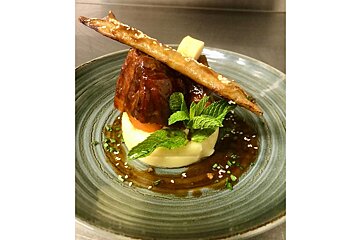 A plate of food with a piece of meat on top of mashed potatoes