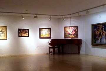 a piano with painting on the wall near it