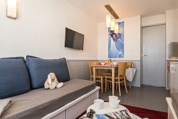 A teddy bear sits on a couch in a living room