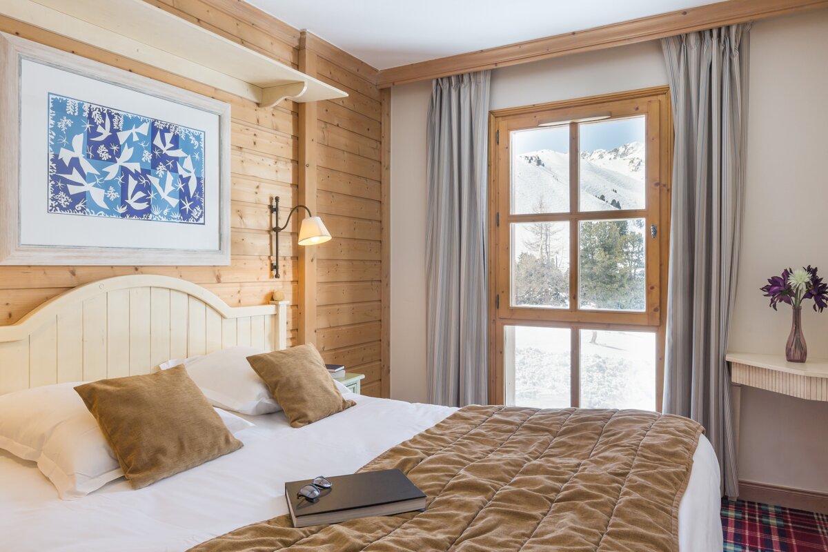 A bedroom with a painting on the wall above the bed