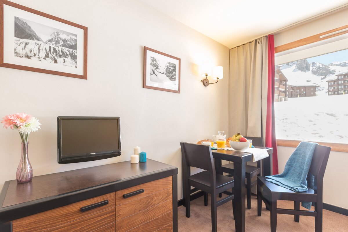 A room with a table and chairs and a flat screen tv
