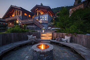 A fire pit sits in front of a large house