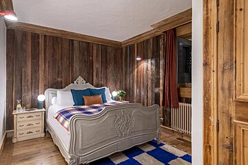 A bedroom with wood paneled walls and a bed