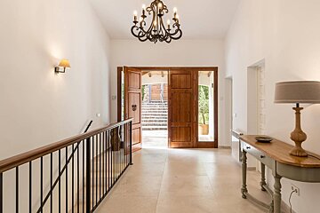 A hallway with a wooden door and a chandelier