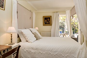 A bedroom with a canopy bed and a painting on the wall