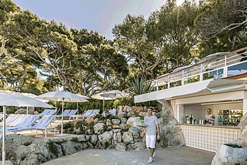 A man standing in front of a bar holding a drink