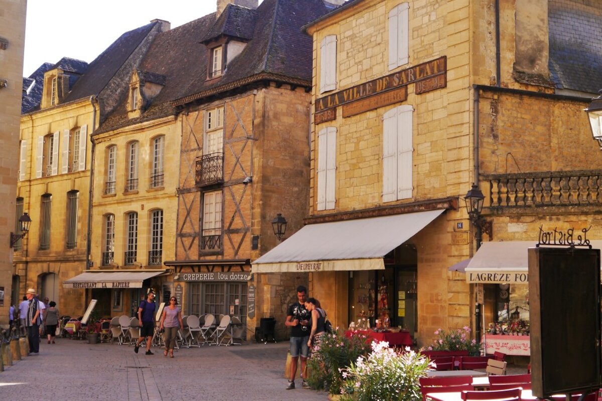 a street with several medieval style honey-coloured buildings in sarlat