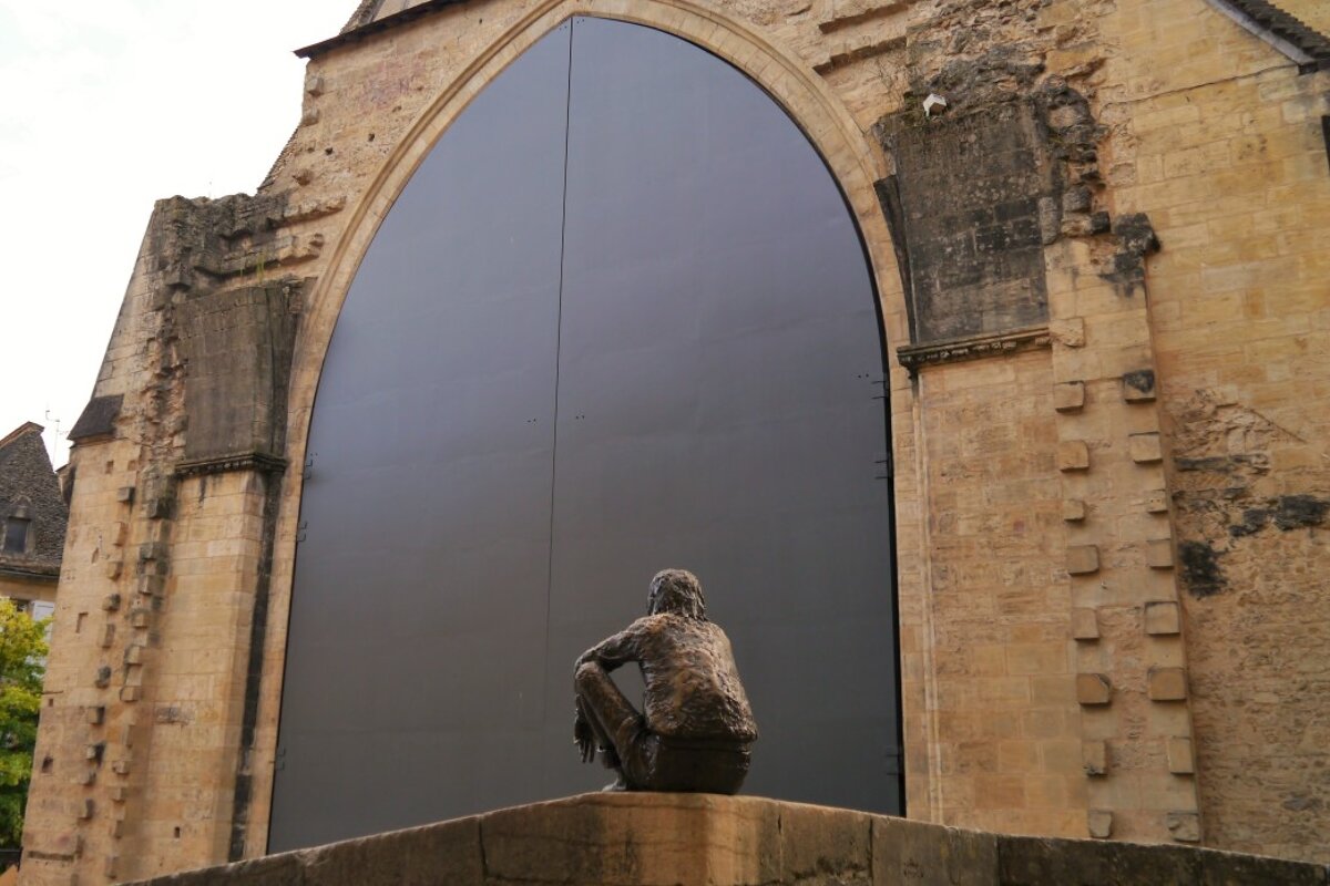 a statue in front of large doors of the main halle in sarlat