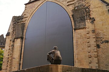 a statue in front of large doors of the main halle in sarlat