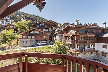 A white van is parked in front of a row of houses