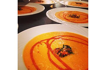 A bowl of soup with a swirl of red sauce on top