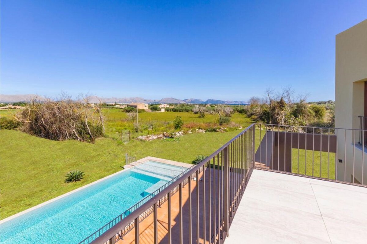 A balcony overlooking a swimming pool with mountains in the background