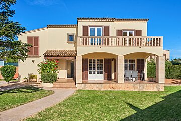 A house with a balcony and a lawn in front of it
