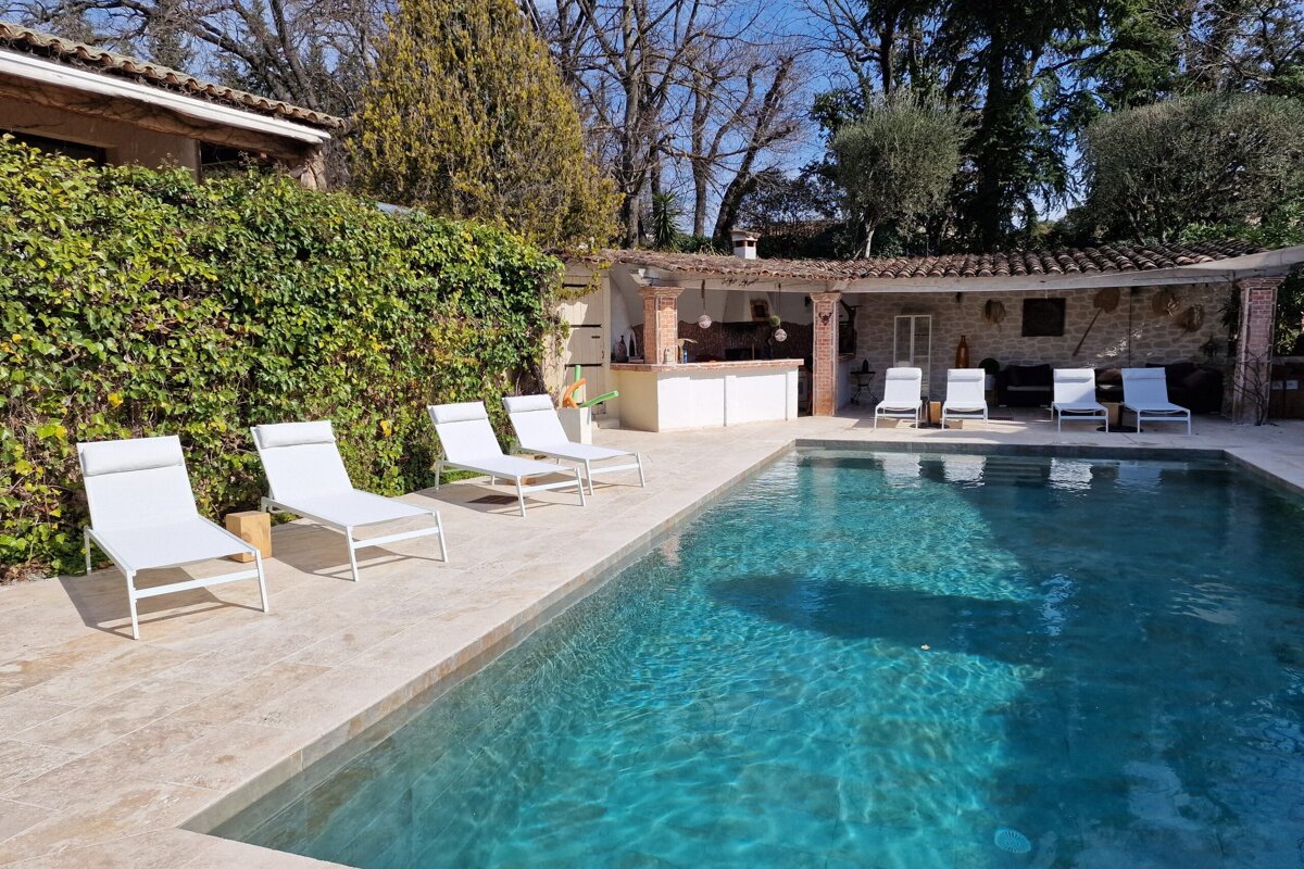 A large swimming pool with white lounge chairs around it