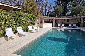 A large swimming pool with white lounge chairs around it