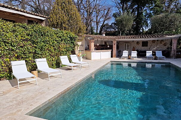 A large swimming pool with white lounge chairs around it