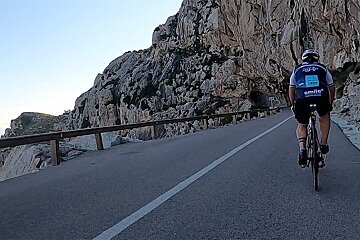 A man is riding a bike down a road and his shirt says smile