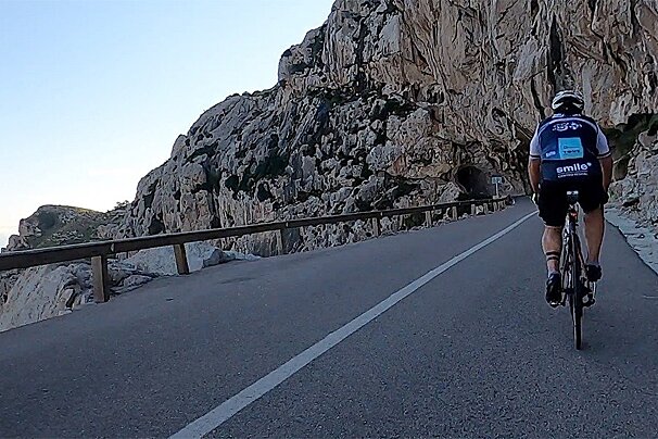 A man is riding a bike down a road and his shirt says smile