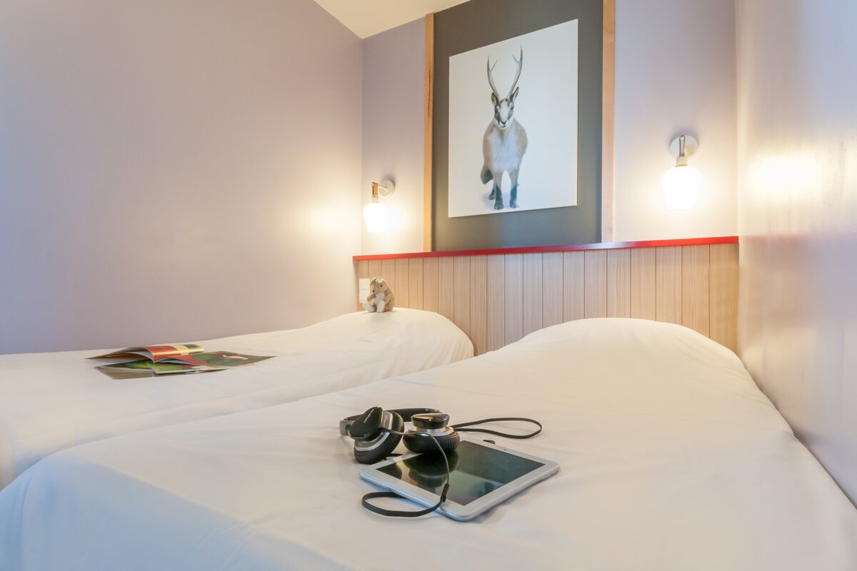 A bedroom with two beds and a picture of a deer on the wall