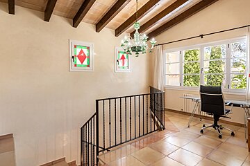 A staircase with a desk and chair and a stained glass window