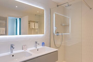 A bathroom with two sinks and a walk in shower
