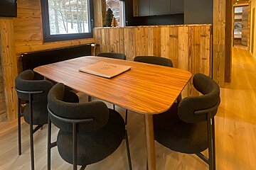 A wooden table with black chairs and a book on top that says ' l' atelier ' on it