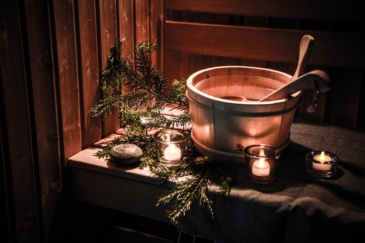 A wooden bucket with a spoon in it sits next to candles