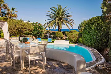 A swimming pool with a table and chairs in front of it