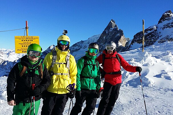 four skiers posing near a danger sign