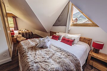 A bed with a fur blanket and red pillows in a bedroom