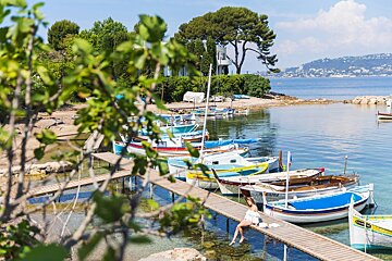 A woman sits on a dock next to a row of boats one of which has a yellow sign on the side