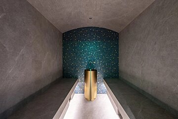 A bathroom with a blue tile wall and a gold sink