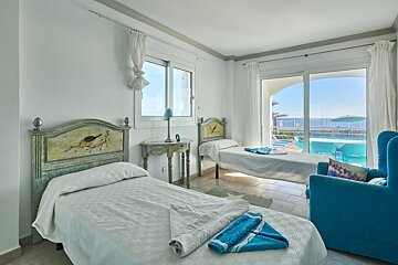 A bedroom with two beds and a blue chair