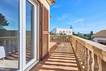 A balcony with a stone railing and shutters on a sunny day