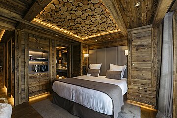 A bedroom with a bed and a ceiling made of logs