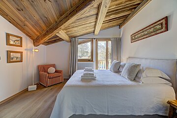 A bedroom with a large bed and a chair