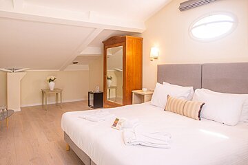 A hotel room with a large bed and a round window