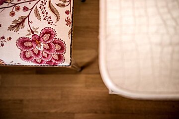 A chair with a pink flower on it sits next to a white mattress