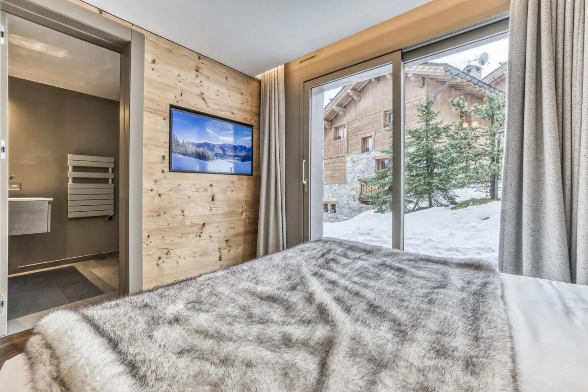 A bedroom with a sliding glass door and a television on the wall