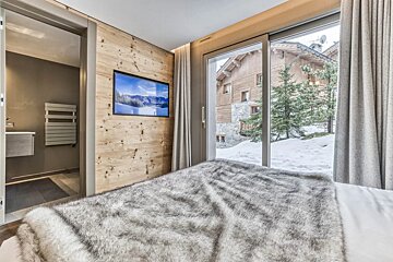 A bedroom with a sliding glass door and a television on the wall